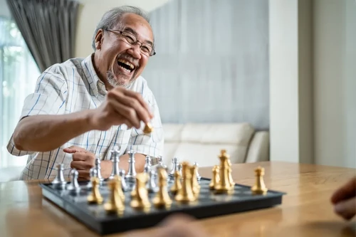 A smiling man engaging with his hobbies through a friendly game of chess.