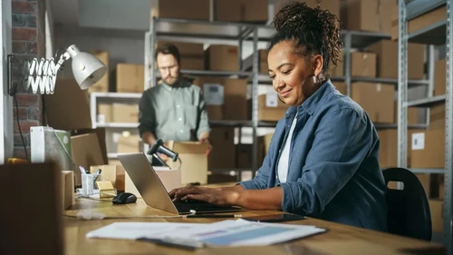 Two business partners organizing their stock in a warehouse.