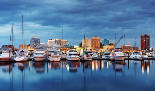 A row of boats docked in Chesapeake, VA, with the city behind them.