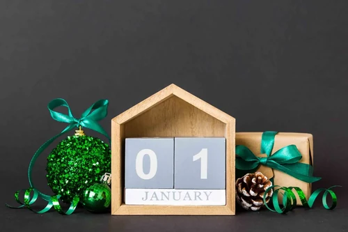 A wooden calendar surrounded by holiday decorations saying “January 01,” symbolizing the new year.