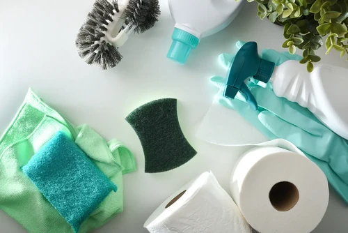 An assortment of spring cleaning tools spread across a kitchen countertop.